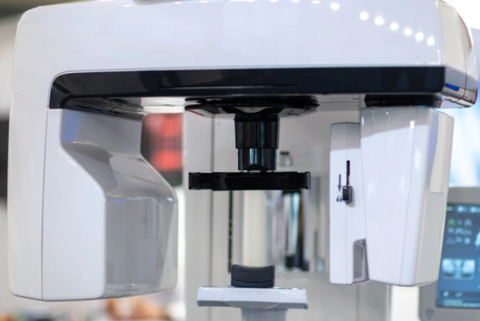 Dental laboratory analyzer machine with white exterior and black components in clinical setting.