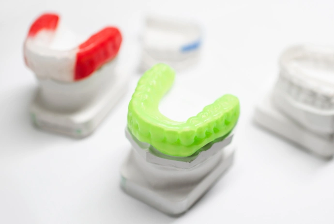 Colorful dental aligners and retainers displayed on white stands, showcasing orthodontic treatment options.