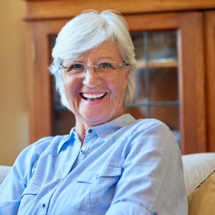 Smiling dental professional wearing glasses and blue shirt in modern office setting.