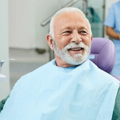 Smiling senior man in dental bib at dentist office during checkup.