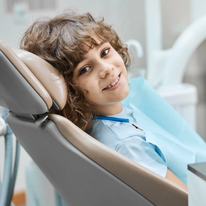 Young child smiling in dental chair during examination at modern dental office.