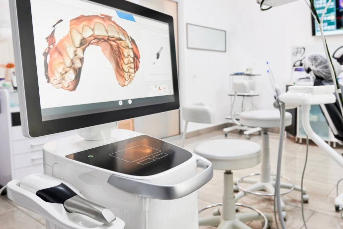 Dental office with 3D imaging scanner displaying orthodontic model on monitor screen.