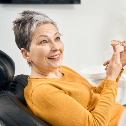 Smiling woman in yellow sweater sitting in dental chair at Brown Road Dental office.