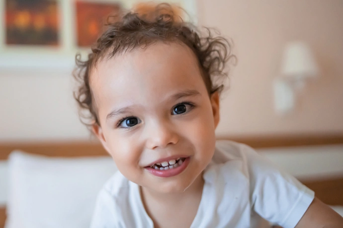 Happy toddler smiling at camera in bright indoor home setting