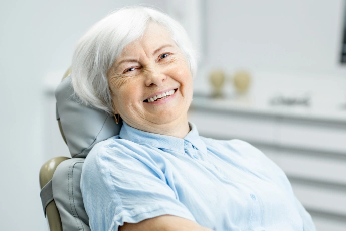Senior woman smiling in dental chair wearing blue bib at Brown Road Dental office