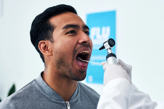 Man receiving dental examination from dentist in clinical setting with blue background.