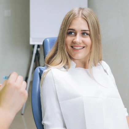 Young woman smiling in dental office chair wearing white top
