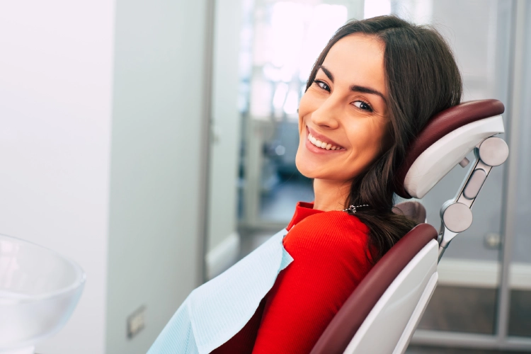 Woman in red shirt smiling in dental chair at modern clinic office