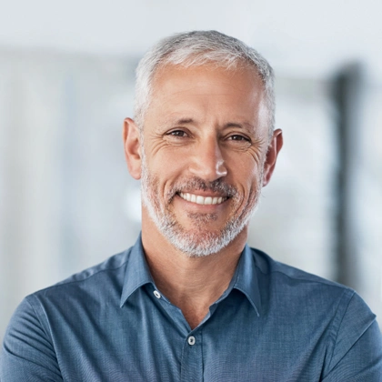 Professional male dentist smiling at camera in modern dental office setting