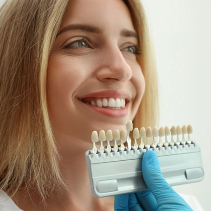 Woman holding dental shade guide showing tooth color samples for cosmetic dentistry consultation.