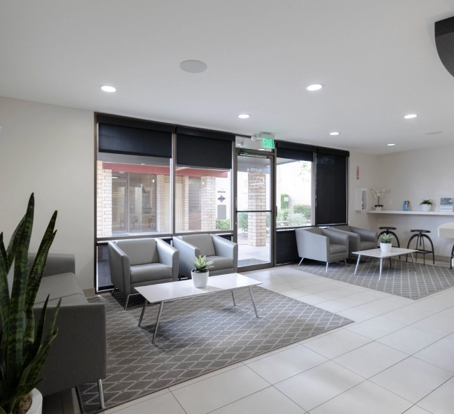 Modern dental office waiting room with seating area, large windows, and contemporary furnishings.