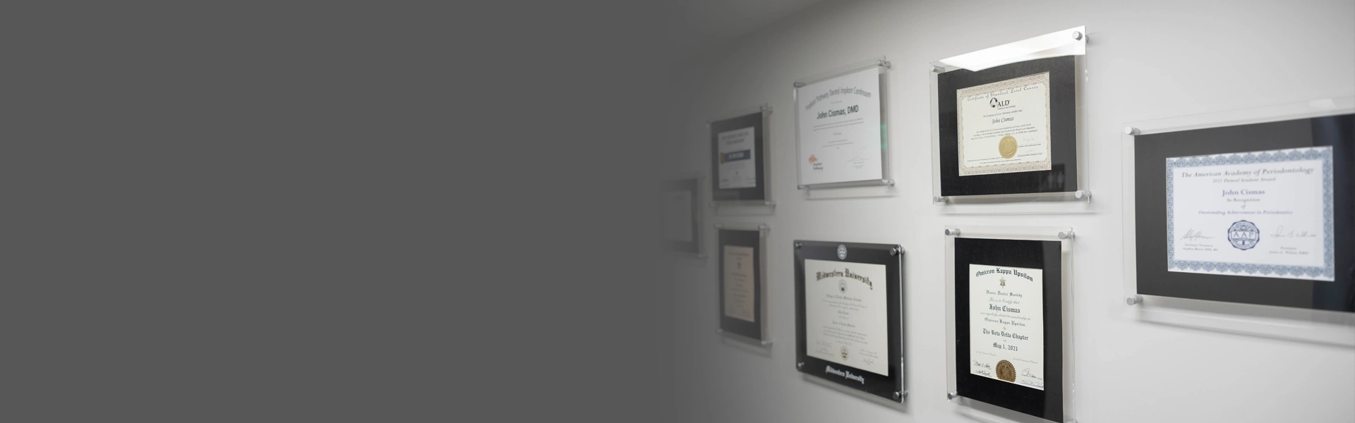Empty picture frames mounted on gray dental office wall in various sizes.