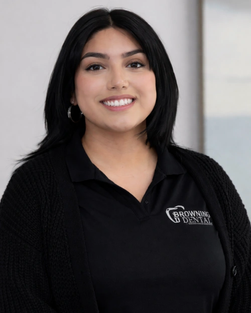 Professional headshot of smiling woman wearing black Brown Road Dental branded polo shirt, indoor office setting.