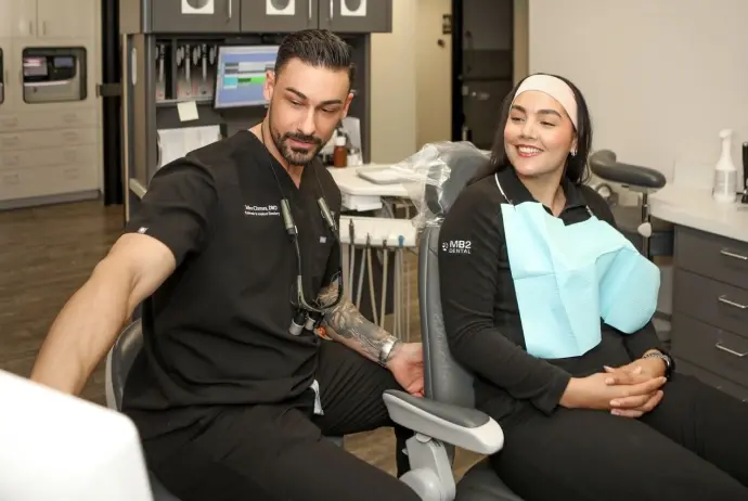 Two dental professionals smiling in treatment room at Mesa dental practice.