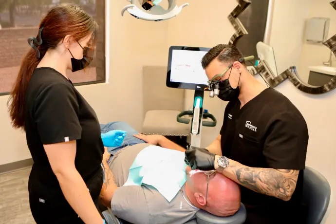 Dental hygienist performing professional teeth cleaning on patient in Mesa dental office.