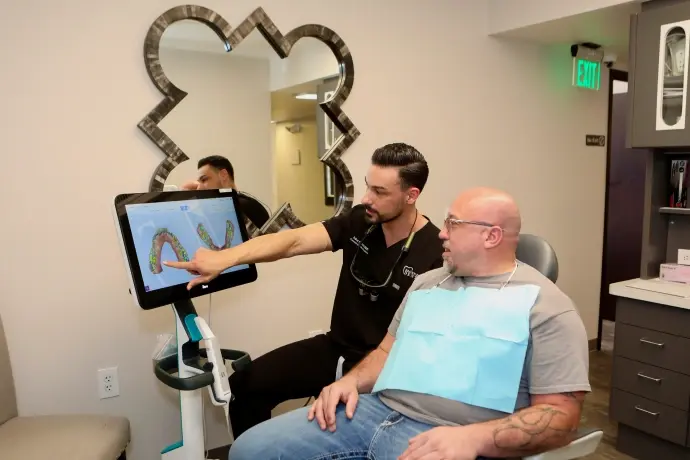 Dentist showing periodontal disease diagram on tablet to patient during consultation.