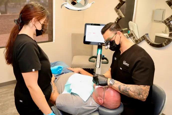 Dentist performing intraoral examination on patient during sedation dentistry consultation in Mesa dental office.